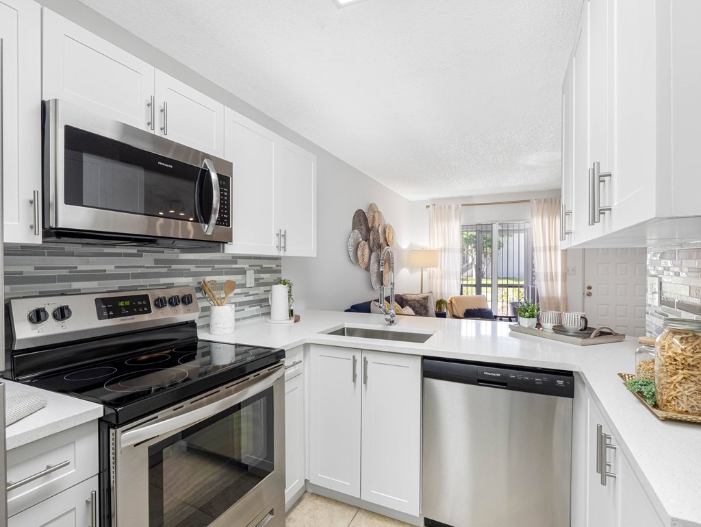 A modern kitchen with white cabinets and stainless steel appliances.